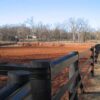 brown fence on the edge of a red dirt field