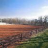 brown fence on the edge of a red dirt field