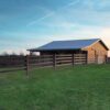 brown fence with a tan barn in the background
