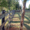 brown fence with a wire strand running along the top of the fence showing a corner of the fence