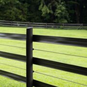 3 rails of black 525 flex fence in the foreground of a green field with the fence continuing in the background.