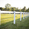 white fence installed on wooden white post in a filed with sunlight