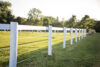 white fence installed on wooden white post in a filed with sunlight