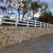 white fence on top of a stone wall