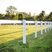 a white fence constructed of coated wire and a top rails of white flex fence