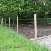 a coated wire fence next to a dirt field