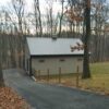 coated wire fence along a asphalt driveway next to a tan stable