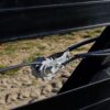 fence tensioner holding coated wire tight between two rails of black flex fence