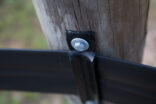 closeup of corner bracket attached to wooden post with a washer and lag bolt