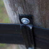 closeup of corner bracket attached to wooden post with a washer and lag bolt