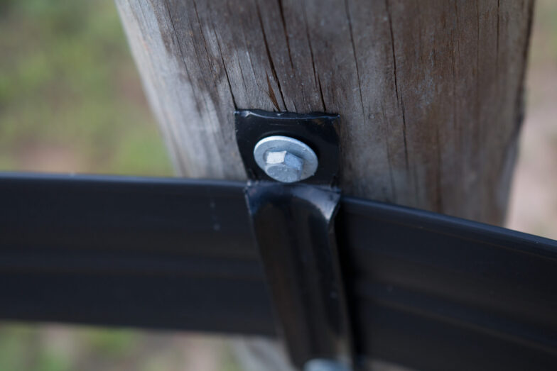 TN TRIP-140 closeup of corner bracket attached to wooden post with a washer and lag bolt